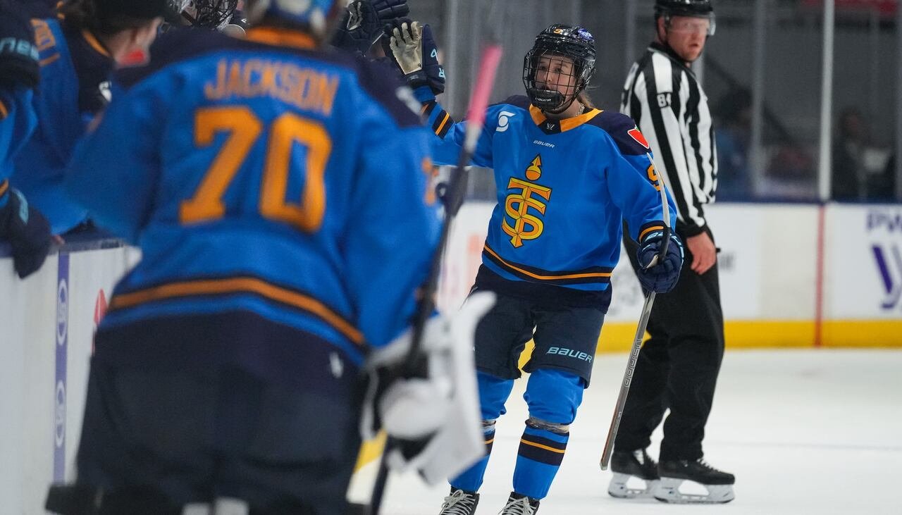 default-174 A hockey player wearing a Toronto Sceptres jersey celebrates a goal with her teammates on the bench.